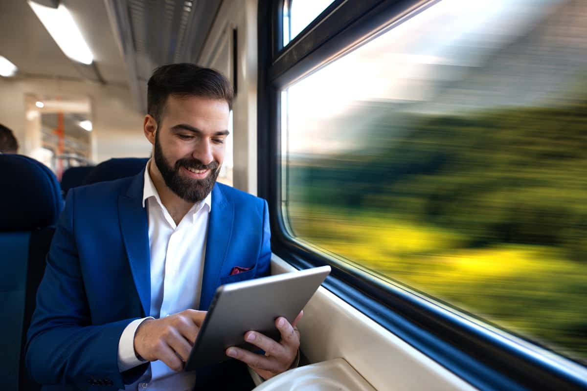 Businessman Sitting Next To Window Reading News And Surfing Inte