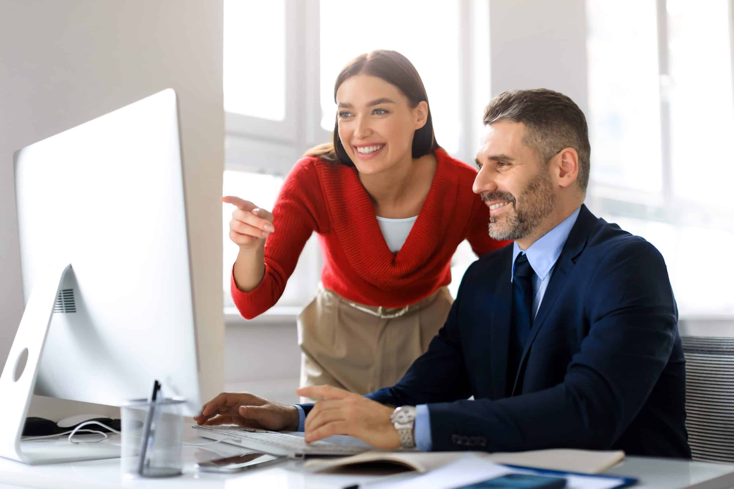 Happy Coworkers Looking At A Computer Screen Together Analyzing Data (1)