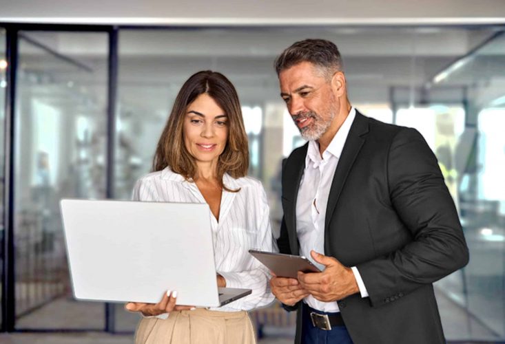 Two people from an insurance carrier looking at life insurance software on a laptop in a modern looking office